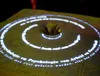 Rings of projected text rippling out from a teacup on a lace tablecloth