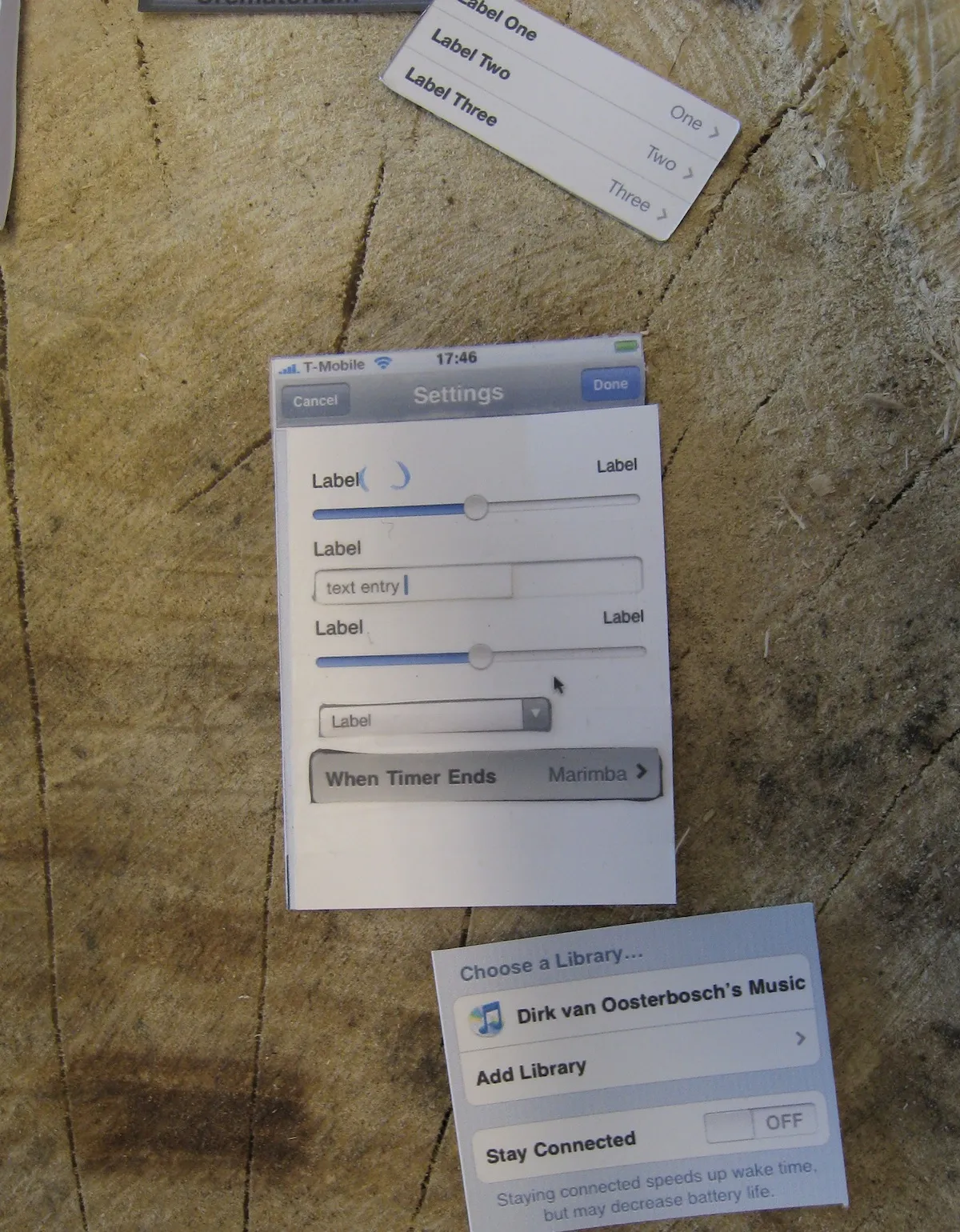 Paper prototype of a settings screen pieced together from cut-out sliders, a text field and a picker, spare table rows beside it