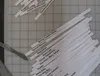 Paper strips printed with interaction design pattern names (Progressive Disclosure, Breadcrumbs, Center Stage…) sorted into piles on a cutting mat, a scalpel and a steel ruler beside them