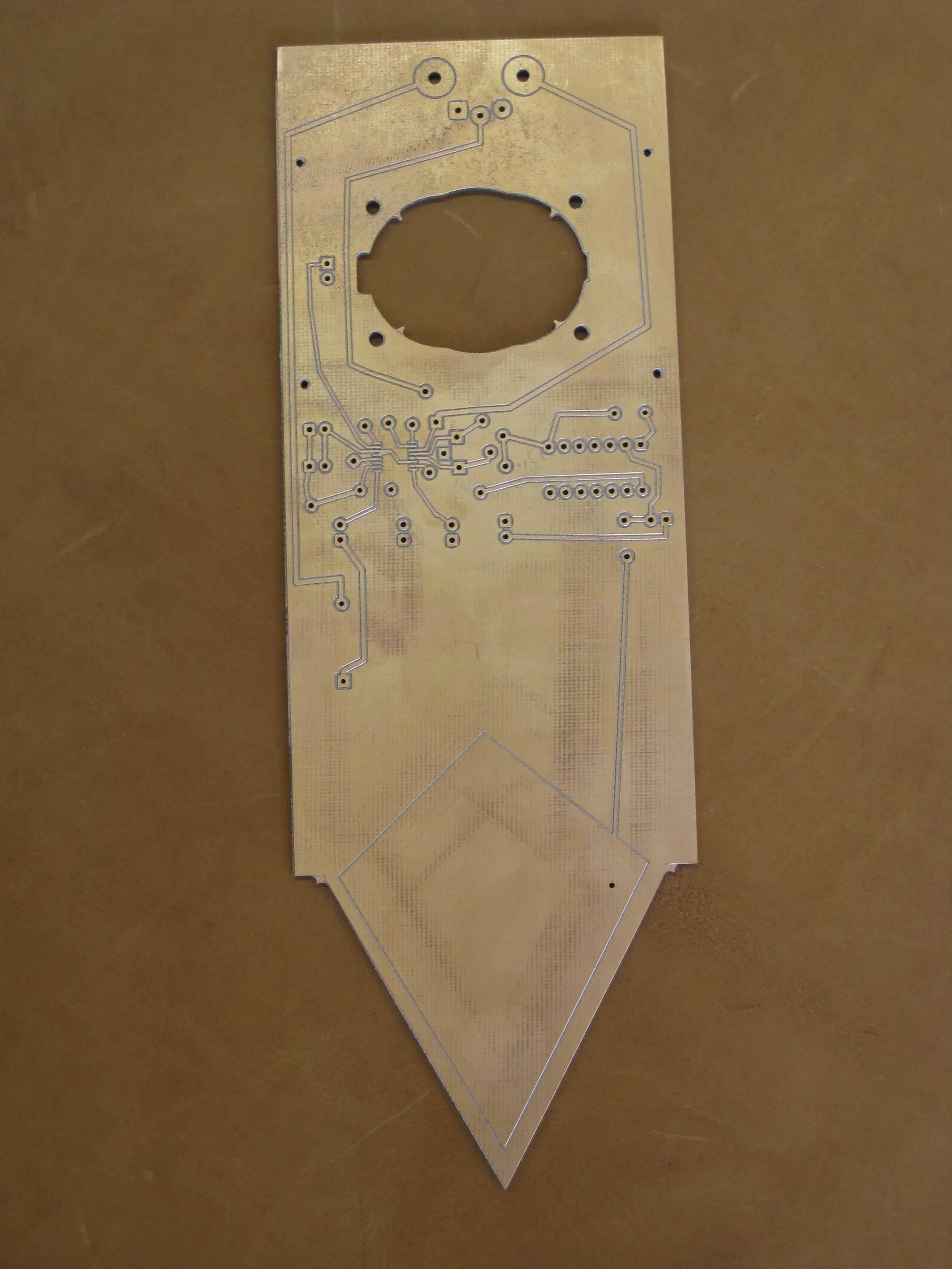 The bare milled circuit board, shaped like a plant stake, with an oval cutout for the speaker