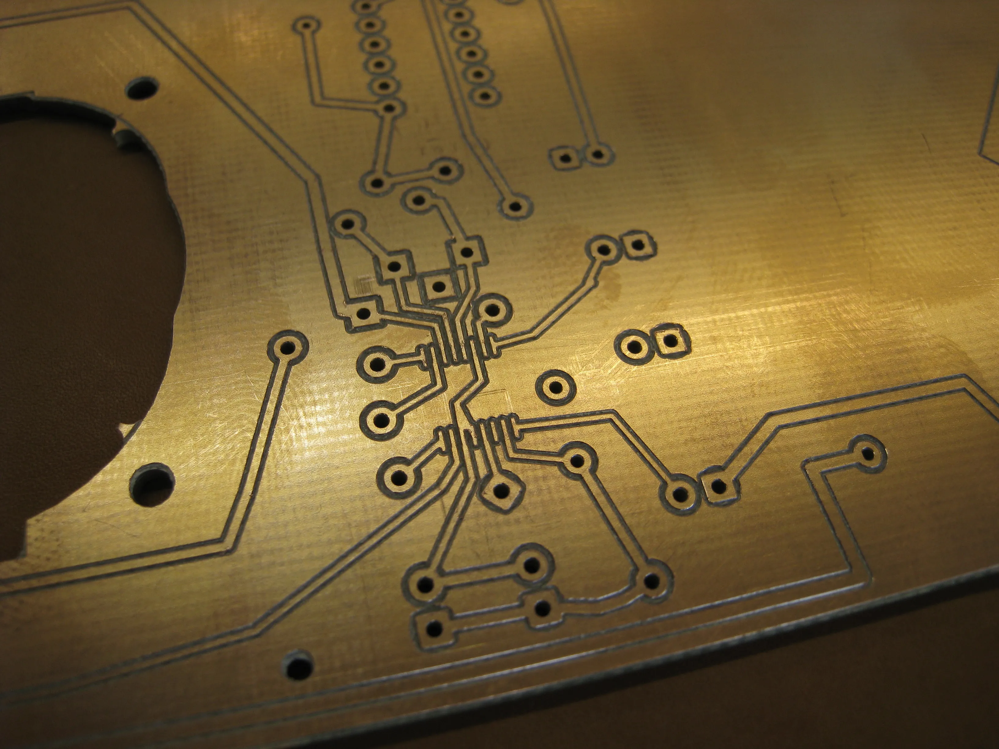 Close-up of the milled copper traces running to the surface-mount chip footprint beside the speaker cutout