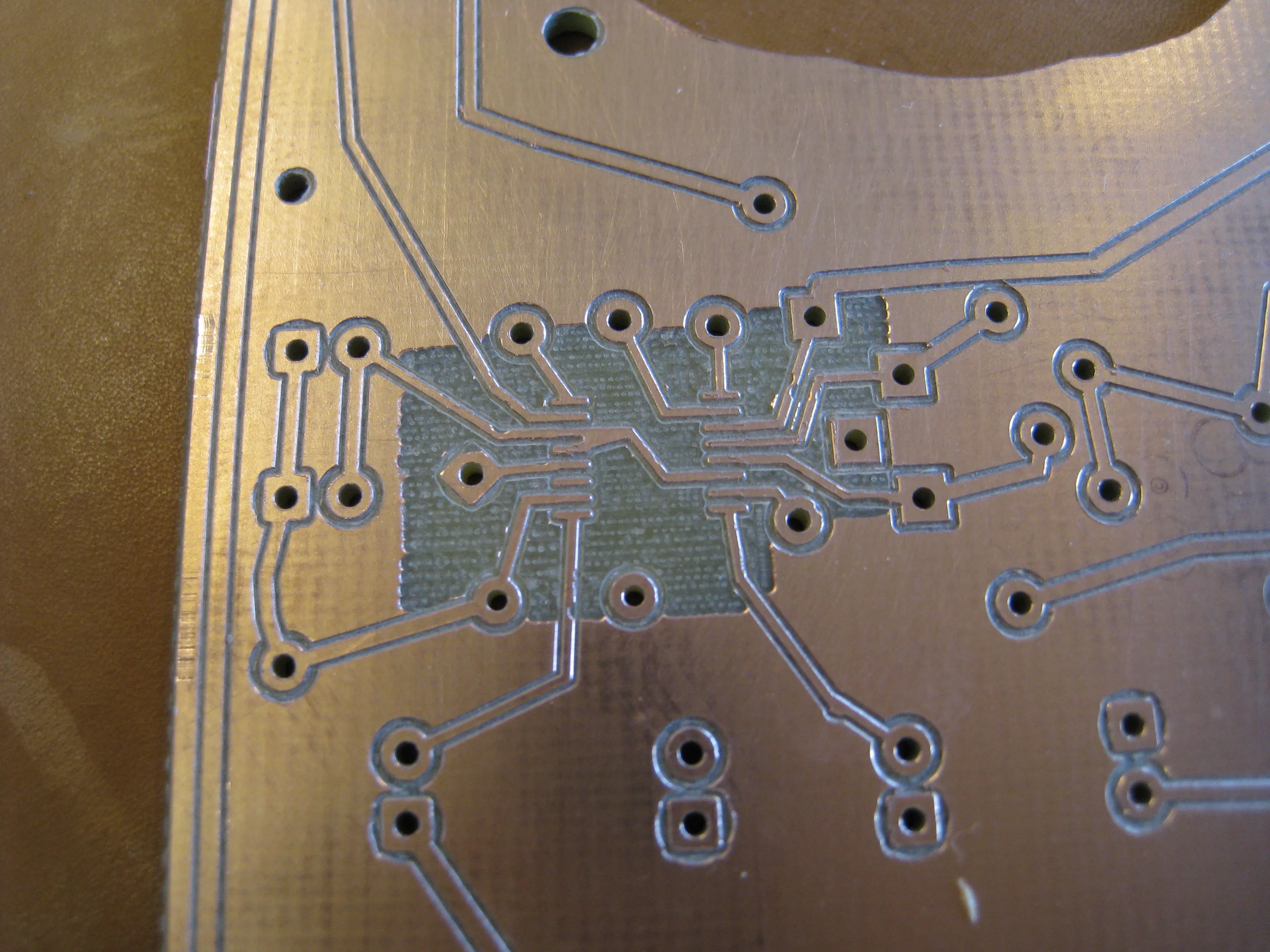 The copper around the chip footprint milled away by hand, leaving a rough patch between the fine traces