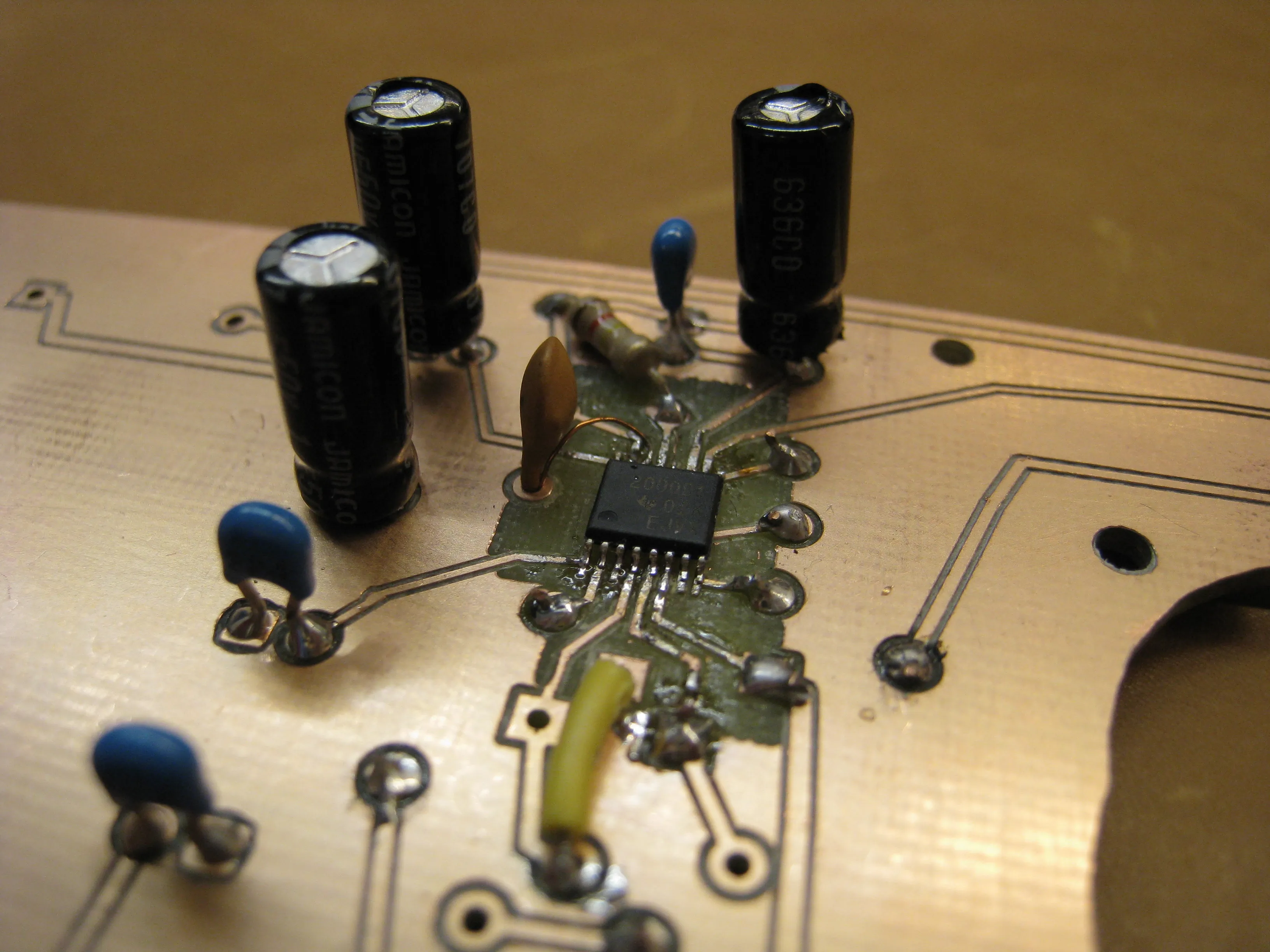 The amplifier chip surrounded by tall electrolytic capacitors and small blue ceramic ones