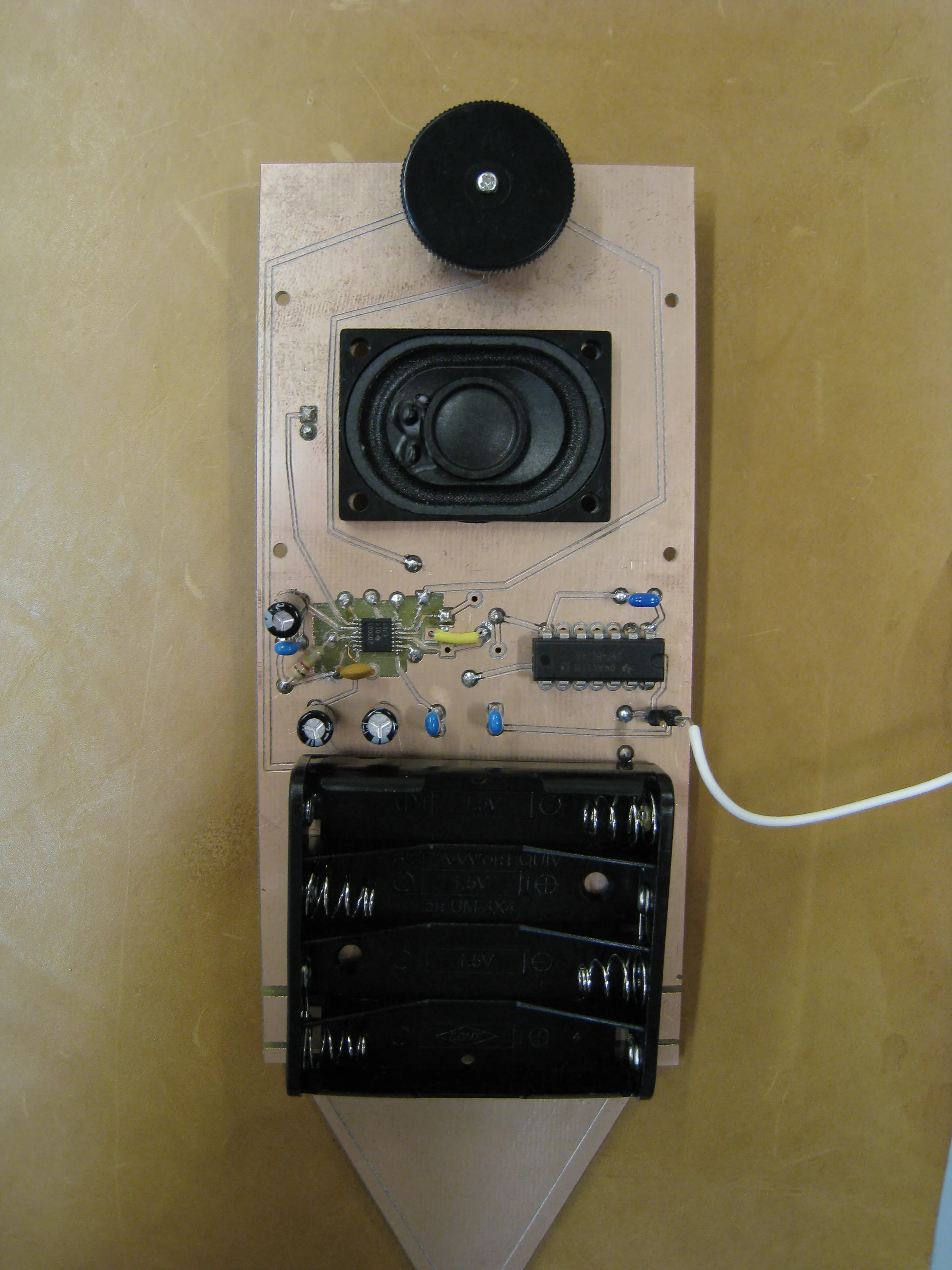 The finished plant-stick board, with a small speaker, a volume knob, the amplifier chips and a four-battery holder above its pointed tip