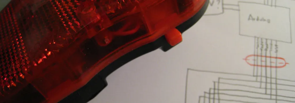 A red bike rear light lying on a hand-drawn wiring sketch of the Arduino circuit