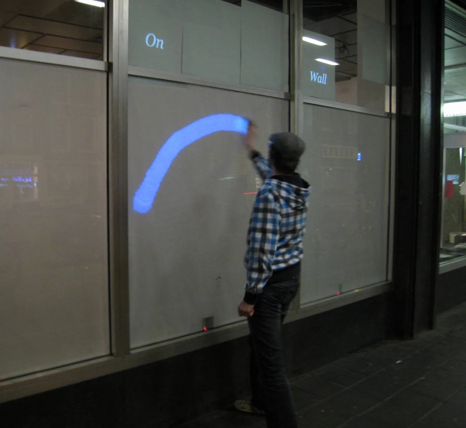 Using a mobile phone to write graffiti on a glass wall
